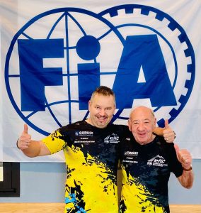 Maciej Serafin pozujący na tle logo FIA