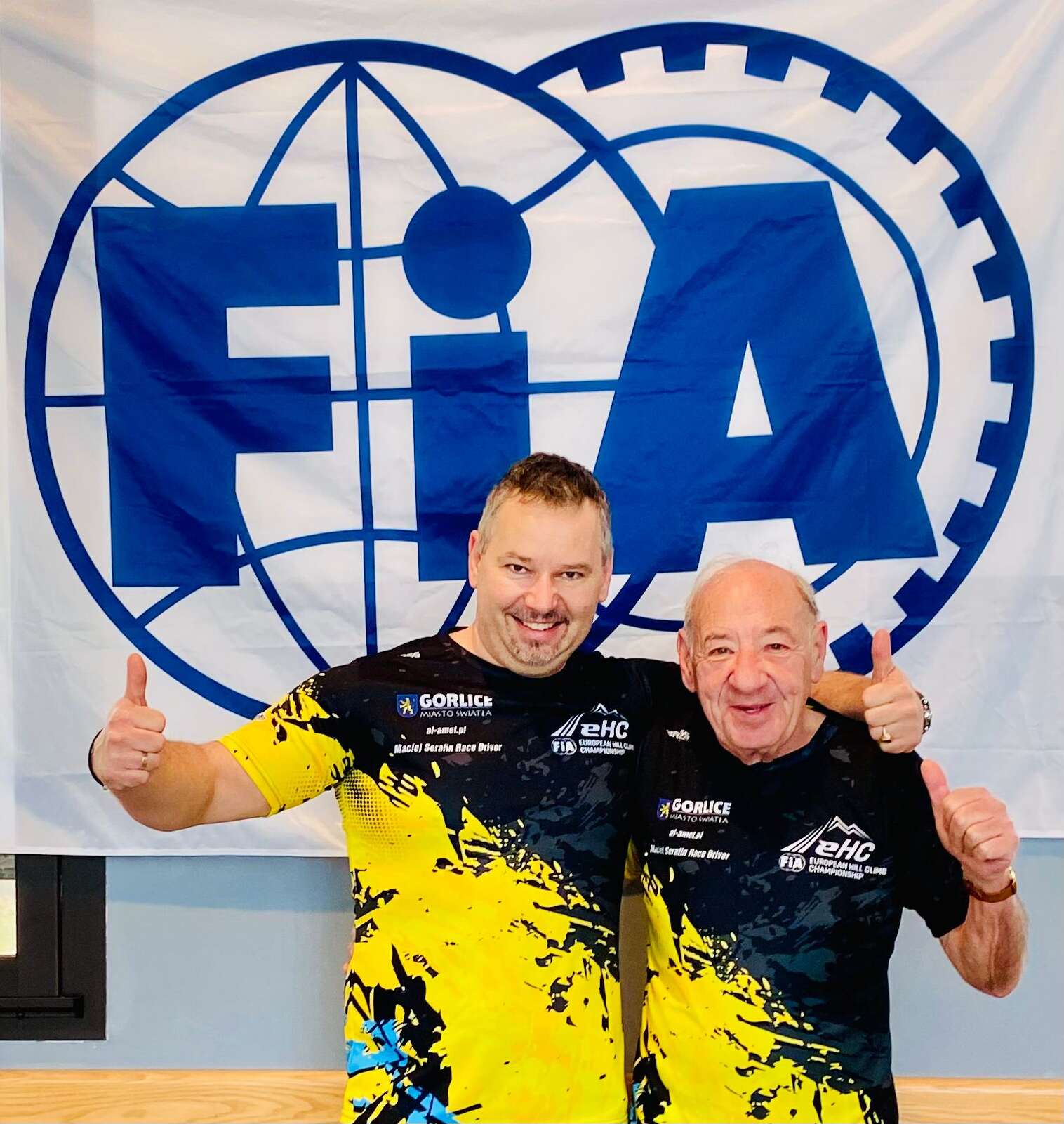 Maciej Serafin pozujący na tle logo FIA